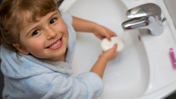 vaikas nuplauna rankas muilu, kad išvengtų kirminų